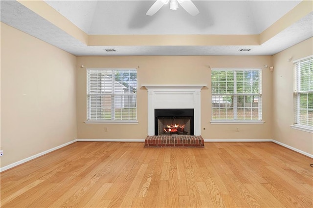 2881 Bridle Creek Dr SW, Conyers, GA 30094 - unfurnished living room with light wood-type flooring, a brick fireplace, a raised ceiling, baseboards, and a ceiling fan