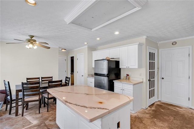 kitchen featuring a textured ceiling, a center island, white cabinetry, freestanding refrigerator, and ceiling fan