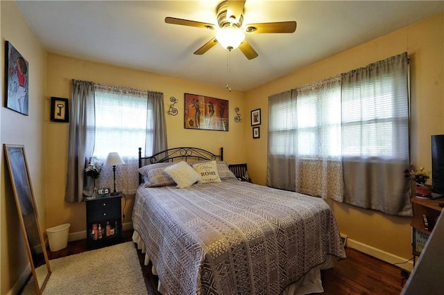 bedroom with ceiling fan, dark wood-type flooring, and multiple windows