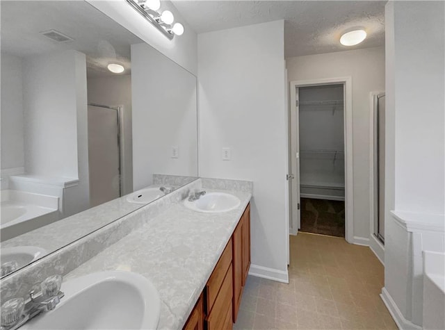 bathroom with a textured ceiling, shower with separate bathtub, and vanity