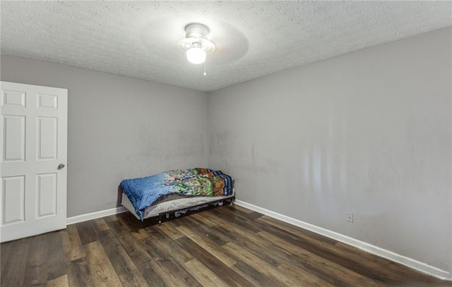 bedroom with a textured ceiling, dark wood-type flooring, and ceiling fan