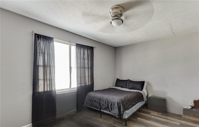 bedroom featuring dark hardwood / wood-style flooring, a textured ceiling, and ceiling fan