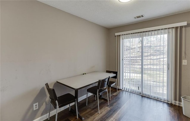 dining area featuring dark wood-type flooring and a textured ceiling