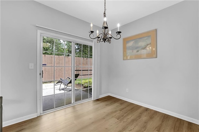 unfurnished dining area with a chandelier, wood finished floors, and baseboards