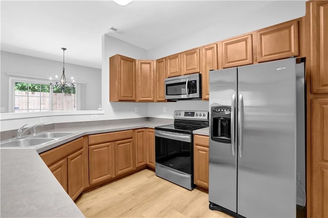 kitchen with stainless steel appliances, a sink, light wood-style flooring, a chandelier, and light countertops