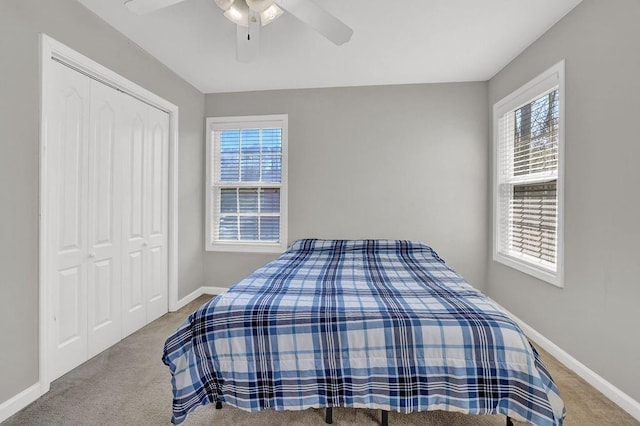 carpeted bedroom featuring a closet, baseboards, and a ceiling fan