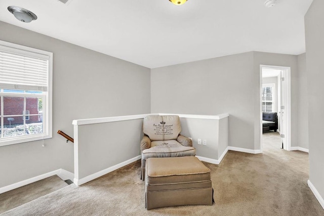 sitting room featuring an upstairs landing, carpet flooring, and healthy amount of natural light