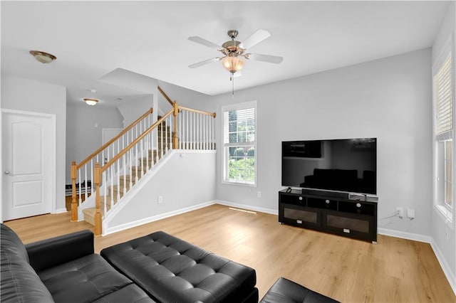 living room featuring stairs, wood finished floors, baseboards, and ceiling fan