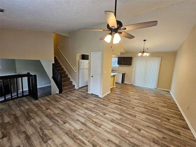 unfurnished living room featuring hardwood / wood-style flooring, ceiling fan with notable chandelier, a textured ceiling, and lofted ceiling