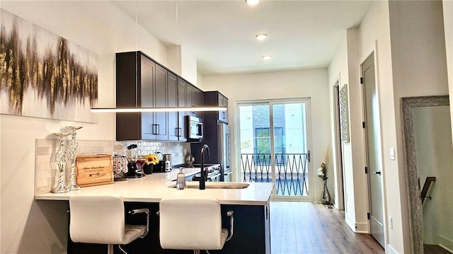 kitchen with sink, a breakfast bar, appliances with stainless steel finishes, backsplash, and kitchen peninsula