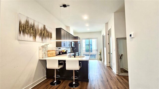 kitchen featuring decorative backsplash, dark hardwood / wood-style floors, kitchen peninsula, and a breakfast bar area