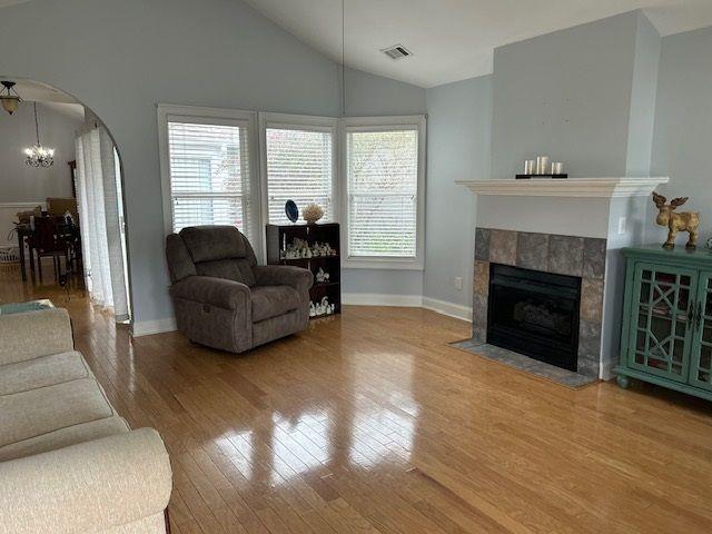 living room featuring a wealth of natural light, visible vents, arched walkways, and wood finished floors