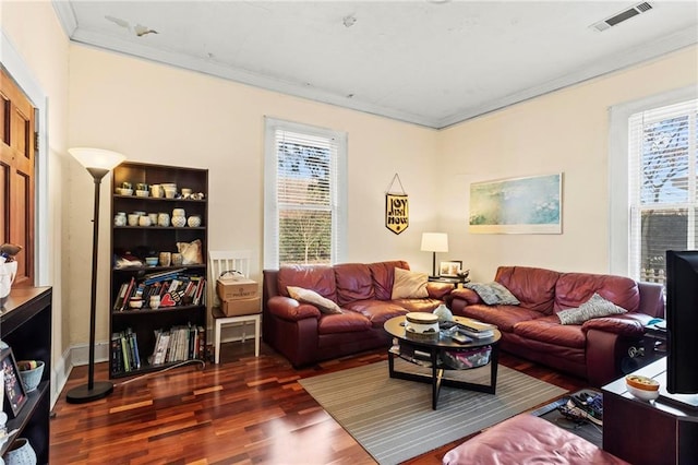 living area with plenty of natural light, wood finished floors, visible vents, and ornamental molding