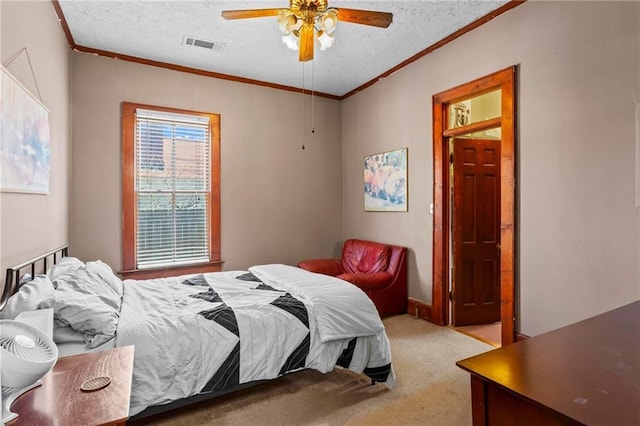 carpeted bedroom featuring ceiling fan, crown molding, visible vents, and a textured ceiling