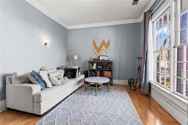 living room with crown molding, wood finished floors, visible vents, and baseboards