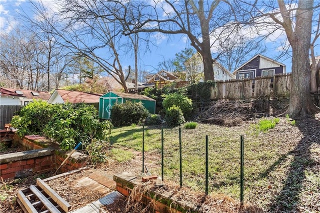 view of yard featuring a storage shed, a garden, a fenced backyard, and an outbuilding