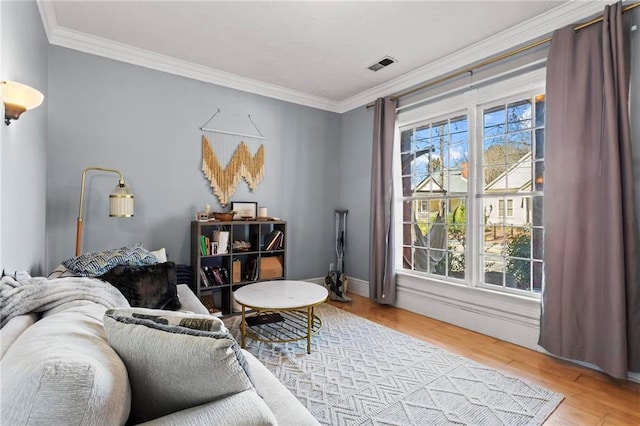 living area featuring visible vents, crown molding, and wood finished floors