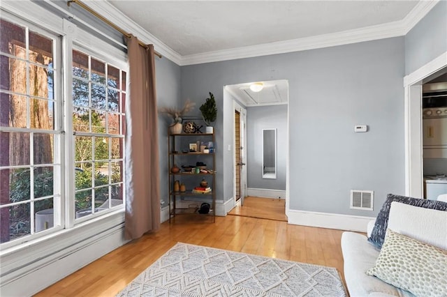 sitting room featuring baseboards, visible vents, light wood finished floors, attic access, and ornamental molding