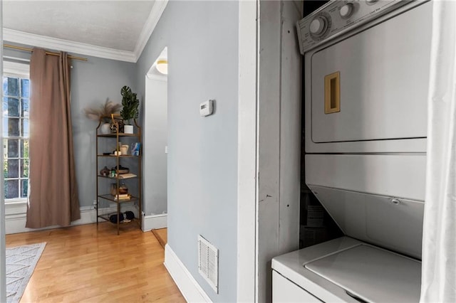 laundry area featuring visible vents, crown molding, light wood-type flooring, laundry area, and stacked washing maching and dryer