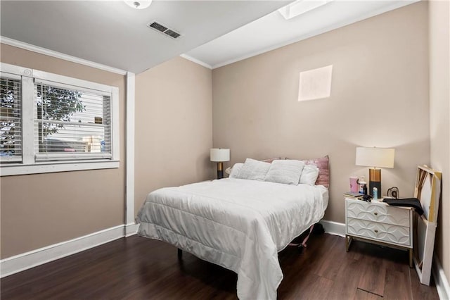 bedroom with visible vents, wood finished floors, baseboards, and ornamental molding