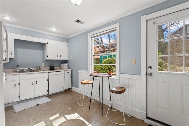 kitchen with visible vents, a sink, white cabinetry, wainscoting, and white dishwasher