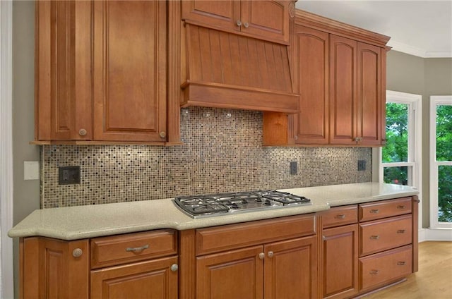 4910 Aldbury Ln, Suwanee, GA 30024 - kitchen with stainless steel gas stovetop, backsplash, light countertops, light wood-type flooring, and crown molding