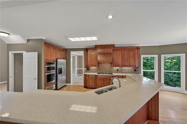 4910 Aldbury Ln, Suwanee, GA 30024 - kitchen featuring appliances with stainless steel finishes, a sink, light wood finished floors, tasteful backsplash, and light countertops