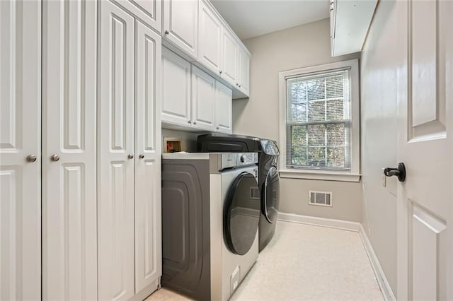 clothes washing area with cabinets and washer and clothes dryer