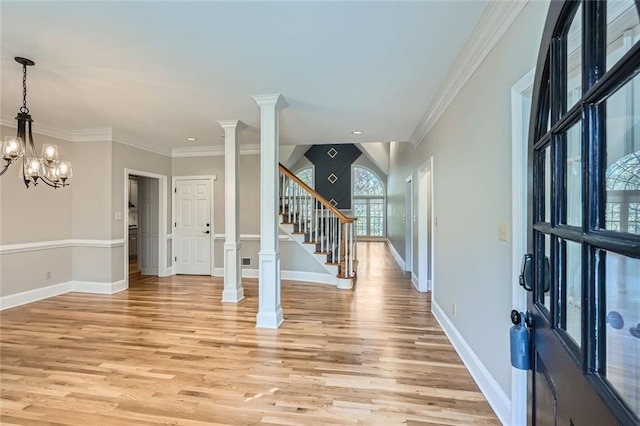 entrance foyer featuring crown molding, a notable chandelier, decorative columns, and light wood-type flooring