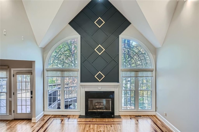 unfurnished living room featuring a wealth of natural light, high vaulted ceiling, and light wood-type flooring