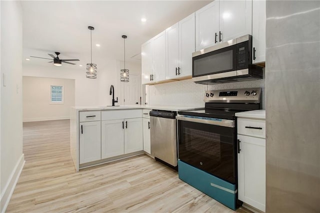 kitchen featuring decorative light fixtures, stainless steel appliances, kitchen peninsula, and white cabinets