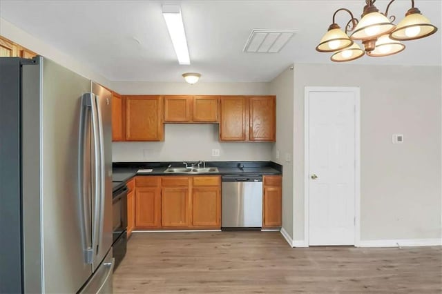 kitchen with pendant lighting, appliances with stainless steel finishes, an inviting chandelier, sink, and light hardwood / wood-style flooring