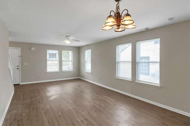 unfurnished room with ceiling fan with notable chandelier and dark wood-type flooring