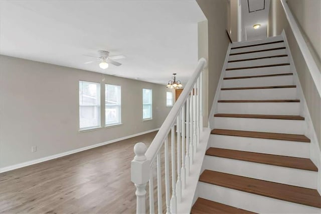 stairway with ceiling fan with notable chandelier and hardwood / wood-style flooring