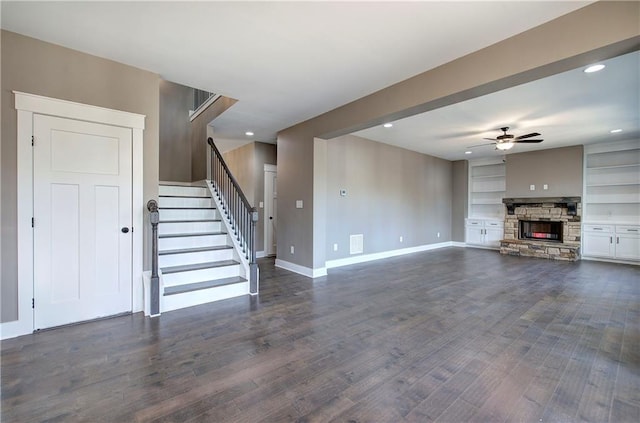 unfurnished living room with baseboards, ceiling fan, dark wood-type flooring, stairs, and a fireplace