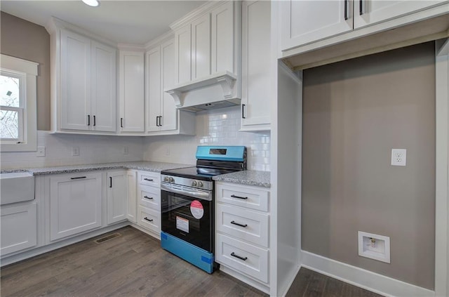 kitchen featuring light stone counters, custom exhaust hood, stainless steel electric stove, visible vents, and white cabinets