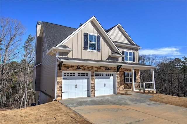 view of front of home with a porch, stone siding, concrete driveway, board and batten siding, and a chimney