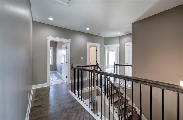 hallway with recessed lighting, baseboards, wood finished floors, and an upstairs landing