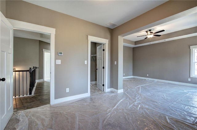 empty room featuring ceiling fan, visible vents, and baseboards