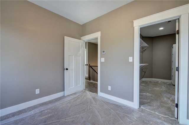 unfurnished bedroom featuring a spacious closet and baseboards