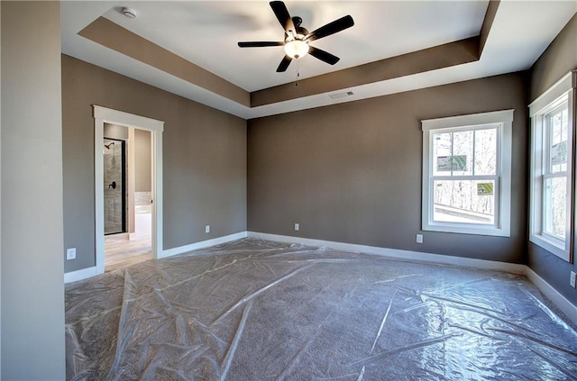 empty room with a raised ceiling, visible vents, and baseboards