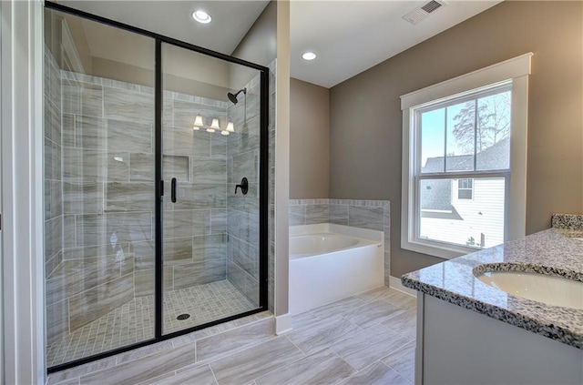 bathroom with visible vents, vanity, a shower stall, a bath, and recessed lighting