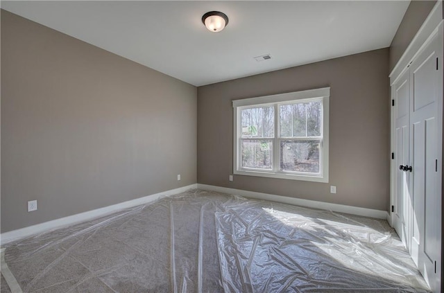 unfurnished bedroom with carpet, baseboards, and visible vents