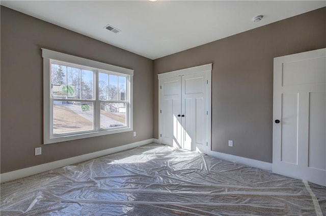 unfurnished bedroom featuring visible vents and baseboards