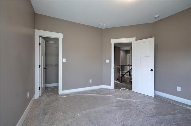 unfurnished bedroom featuring baseboards, visible vents, a walk in closet, and a closet