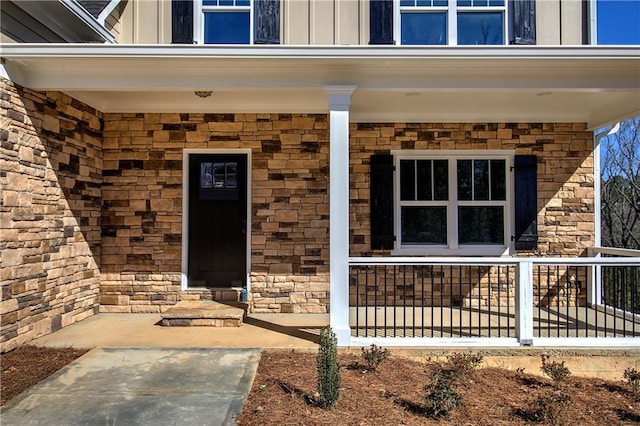 view of exterior entry with stone siding, a porch, and board and batten siding