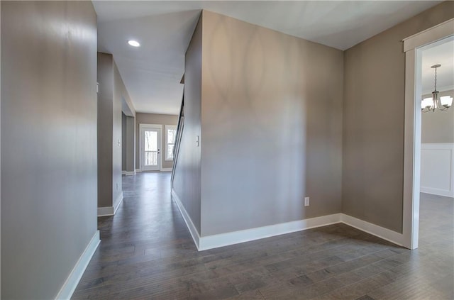 hall featuring baseboards, dark wood-type flooring, recessed lighting, and a notable chandelier