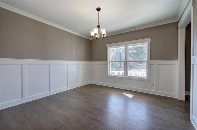 unfurnished room featuring visible vents, dark wood-type flooring, an inviting chandelier, crown molding, and a decorative wall