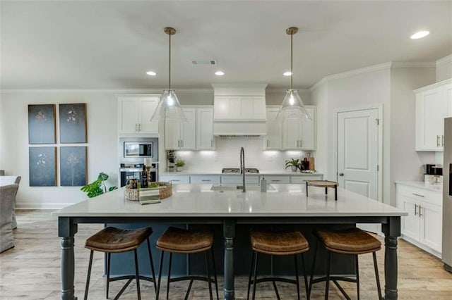 kitchen featuring hanging light fixtures, appliances with stainless steel finishes, and a kitchen island with sink