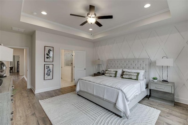 bedroom with ceiling fan, a raised ceiling, and light wood-type flooring